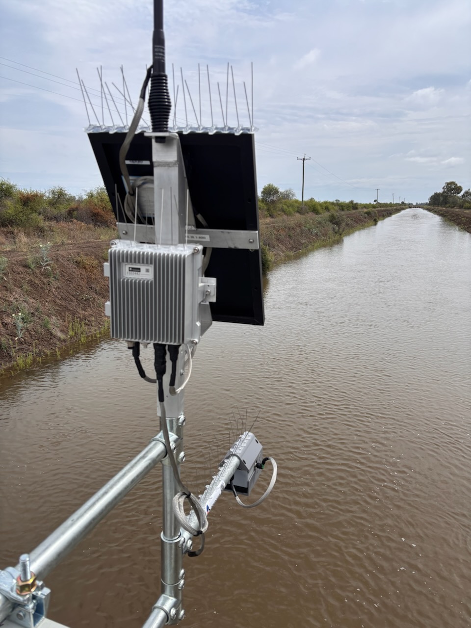 SynaptiX Collector and solar panel mounted on a pole above an irrigation channel, with the radar sensor on an arm below